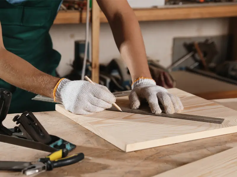 Closeup of a carpenter measuring wooden board